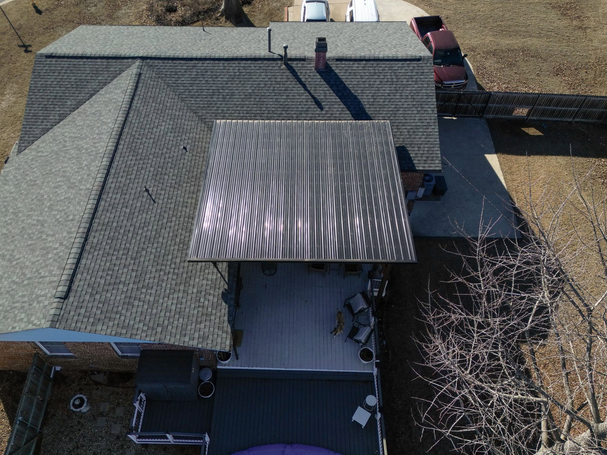 An aerial view shows a dog on a deck next to a house with a metal roofed patio.