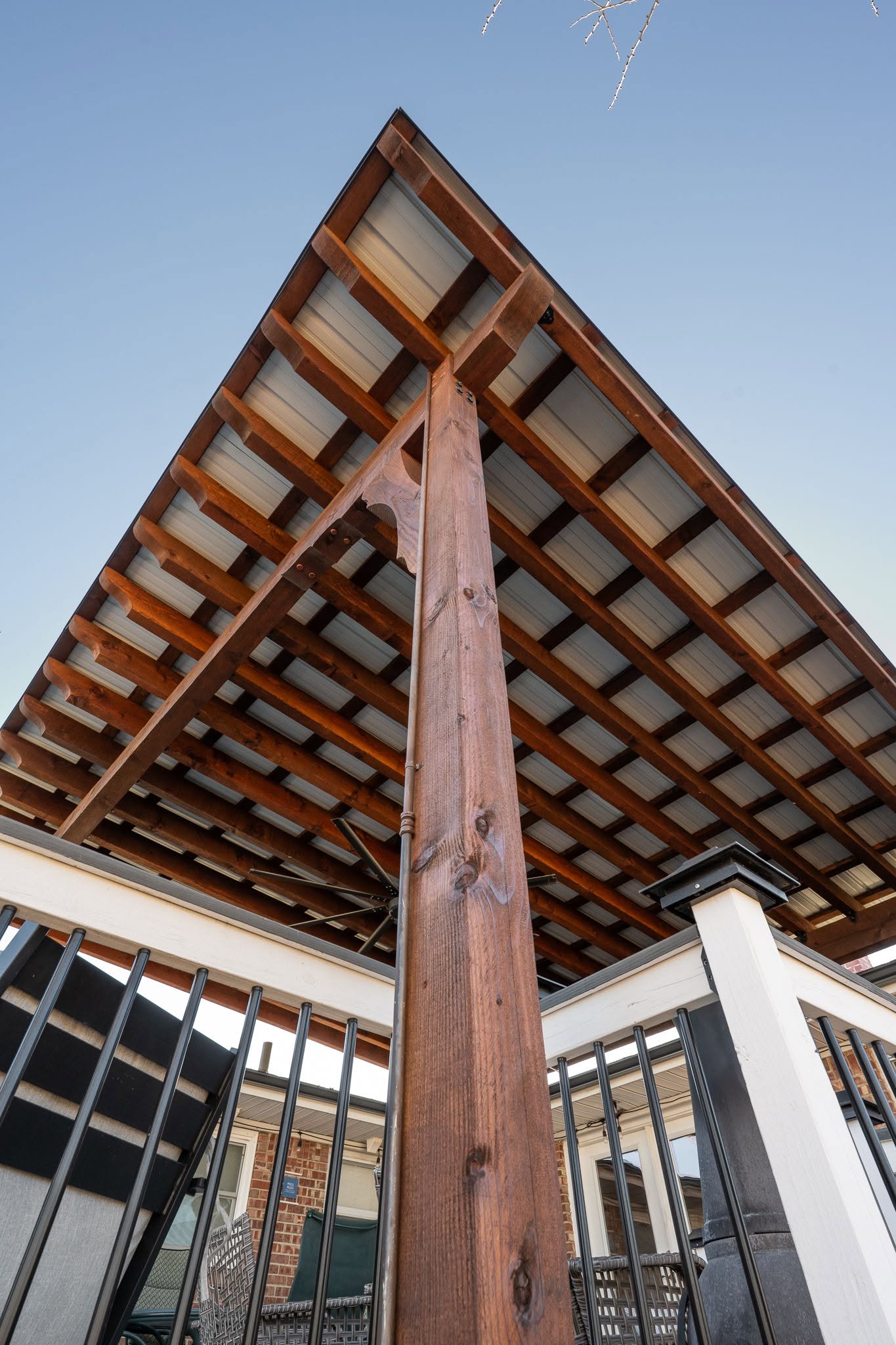 A wooden pergola with a metal roof is shown from a low angle.